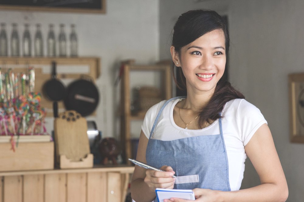 A photo of a happy waiteress patiently listening to her customer