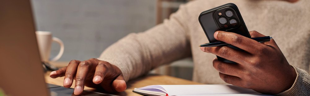 Man with smartphone working on laptop
