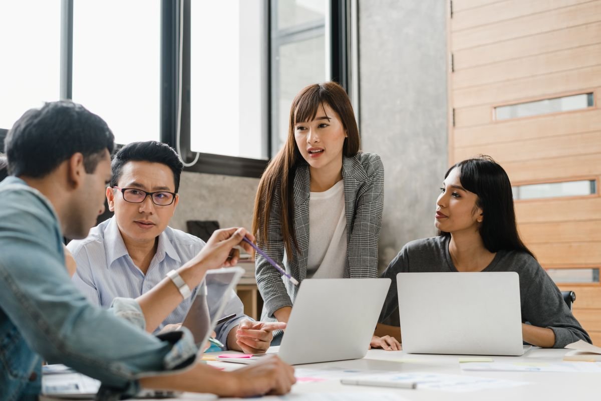 A photo of a group of young creative people in casual wear meeting brainstorming ideas about new paperwork project colleagues working together planning