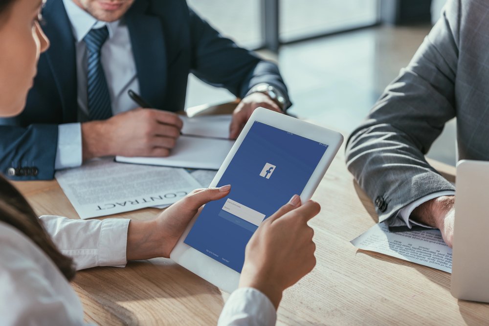 A picture of businessman holding tablet with facebook open