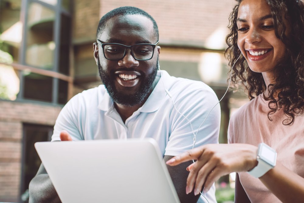 Two people reading on laptop